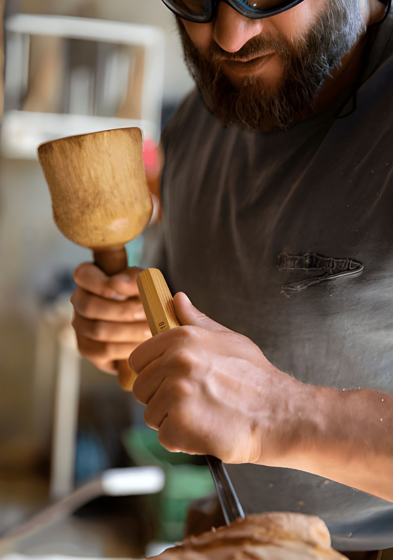 Person, die mit Hammer und Meißel Holz schnitzt.