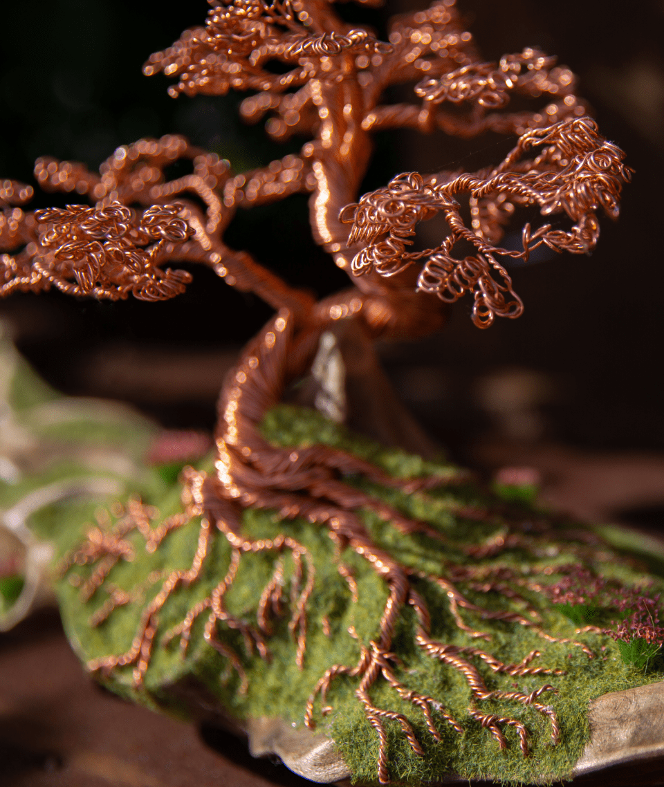 Drahtskulptur eines Kupferbaums auf grünem Moosgrund.