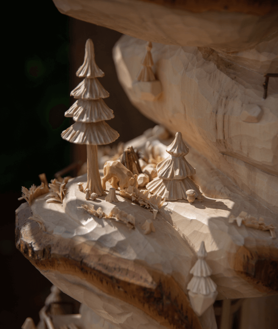 Aufwendige Holzschnitzerei, die Bäume und andere kleine Figuren auf einer Holzoberfläche darstellt.